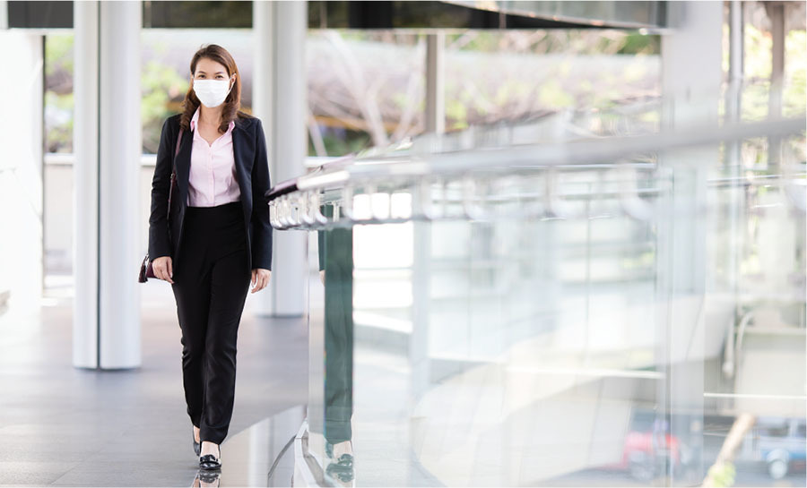 A businesswoman walking at work wearing a mask