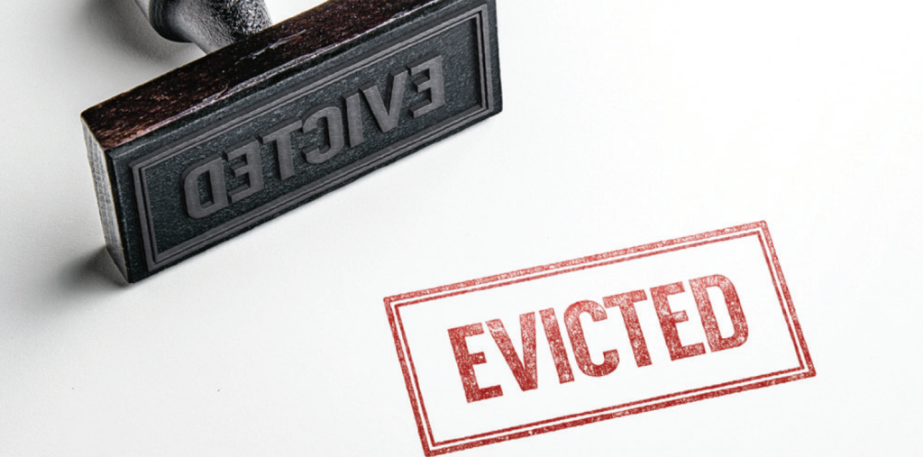 A rubber stamp with the word EVICTED lies next to a stamped red EVICTED mark on a white surface.