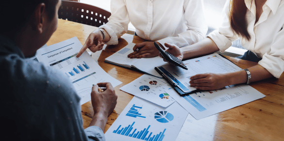 A group working on printed spreadsheets and graphs