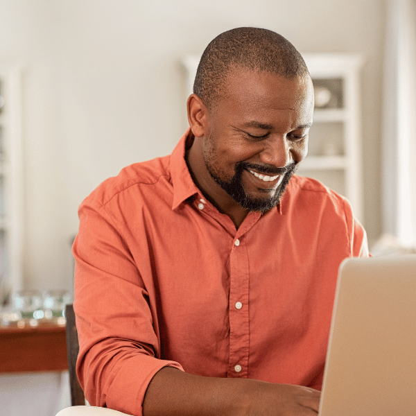 A smiling man working on his laptop